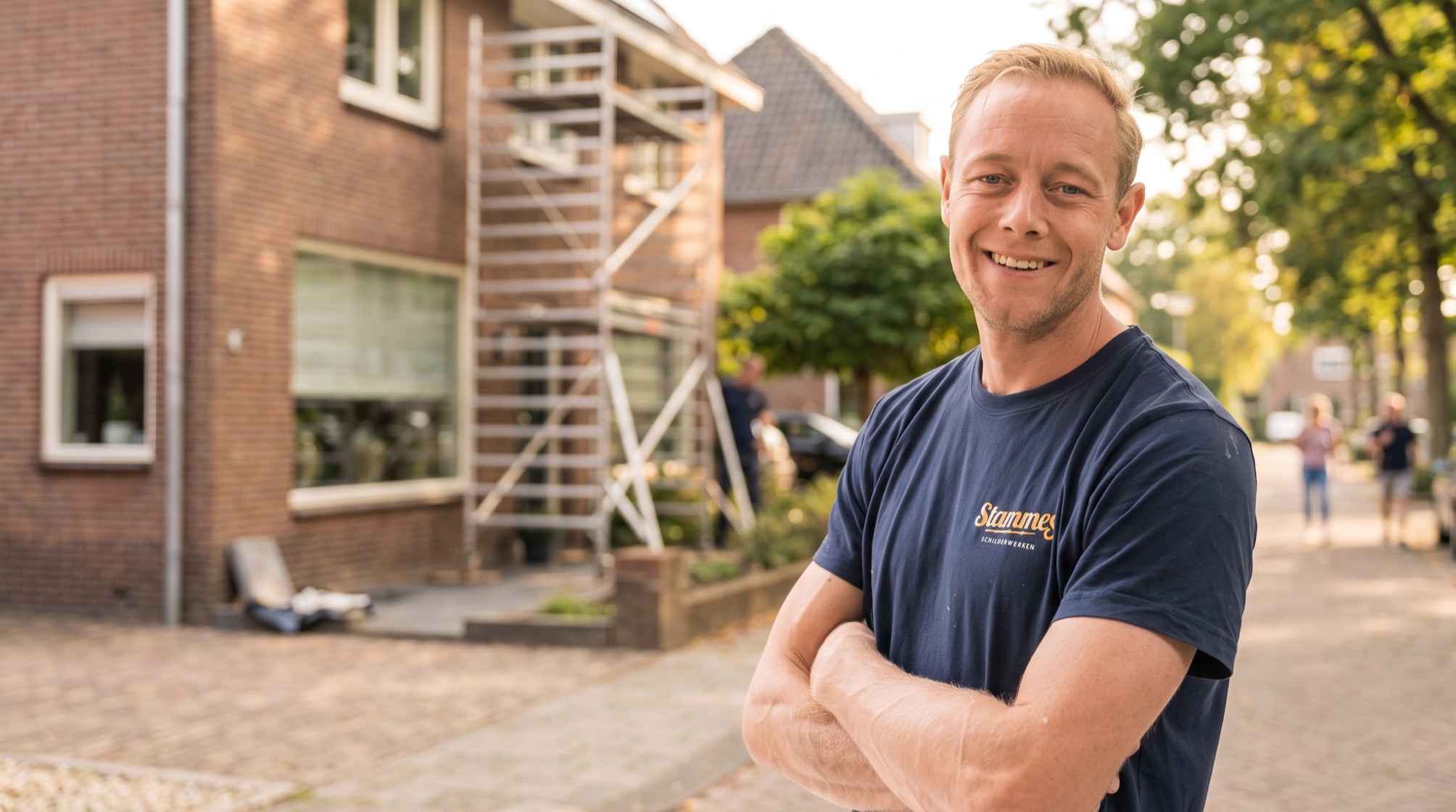 Ondernemer van Stammes Schilderwerken met de armen over elkaar voor een woning met een steiger